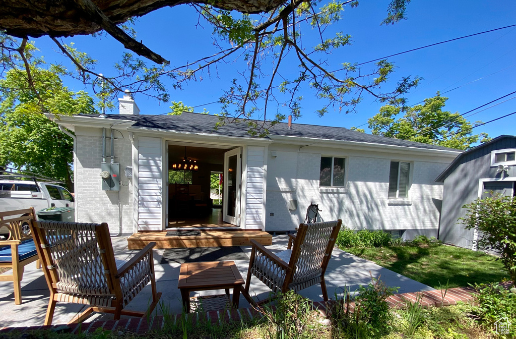Rear view of house with a chimney, brick siding, an outbuilding, and an outdoor living space