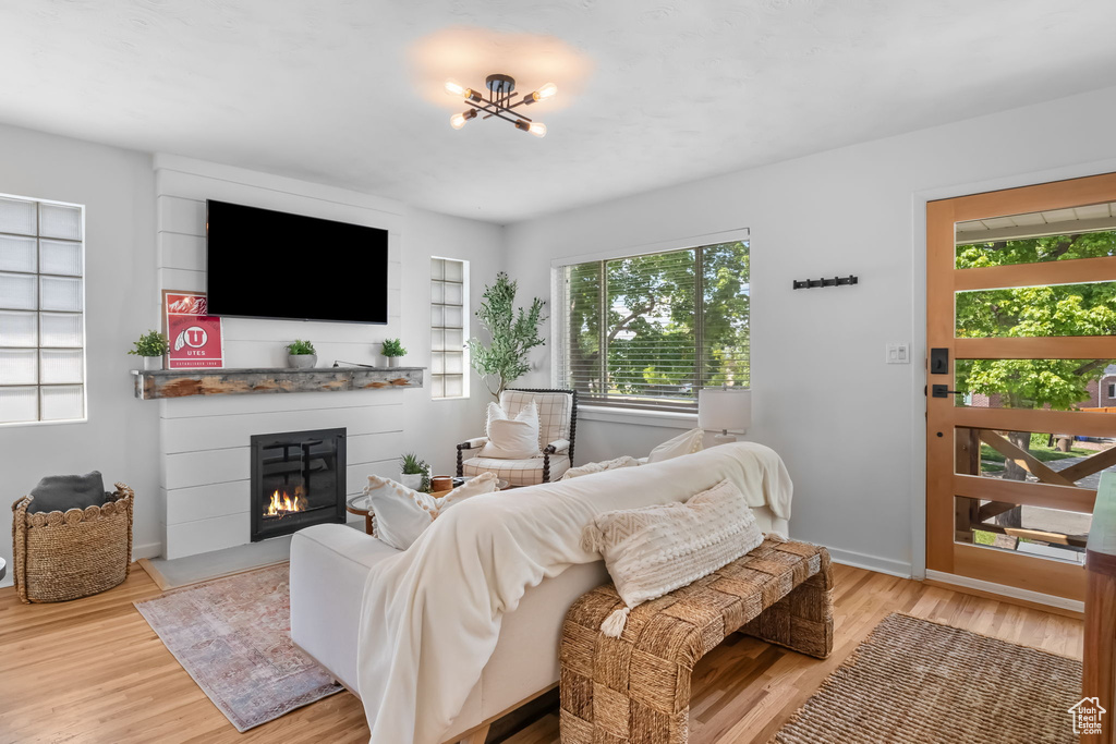 Living area featuring a fireplace with flush hearth, light wood-type flooring, and baseboards