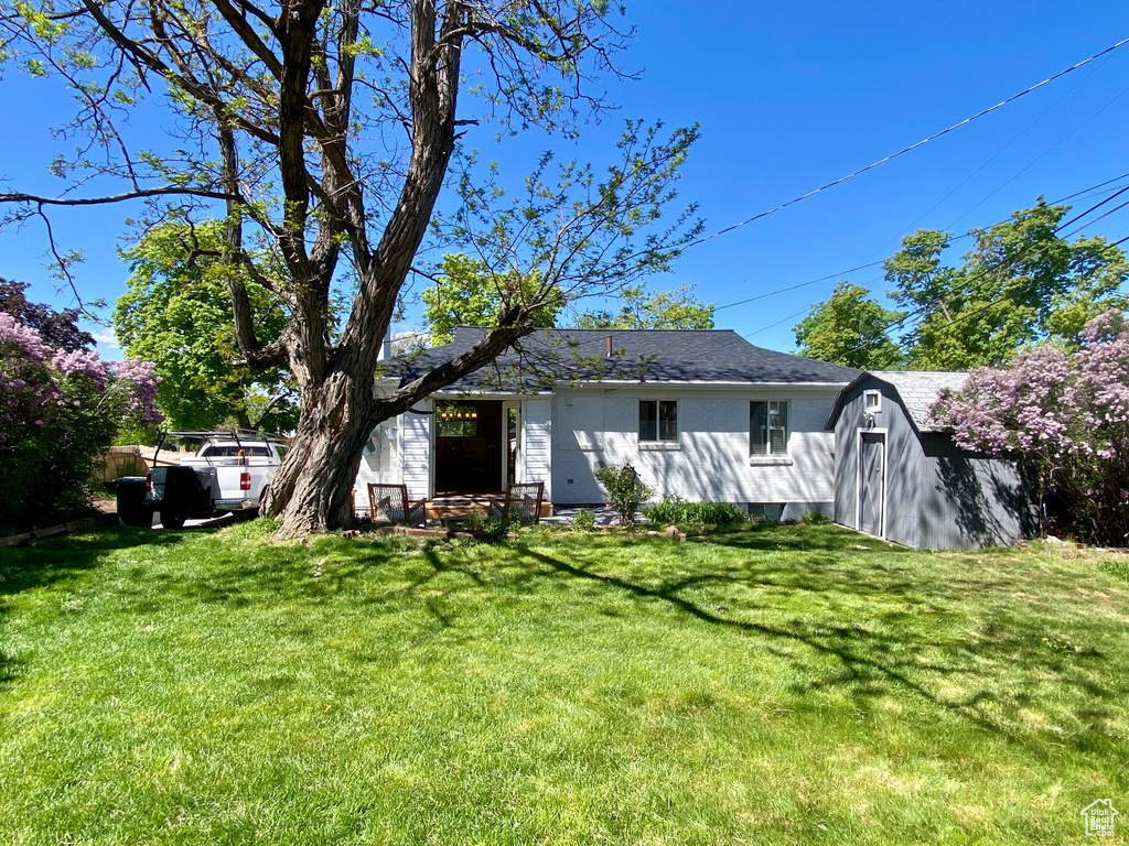 Back of property with a lawn, a shed, and an outdoor structure
