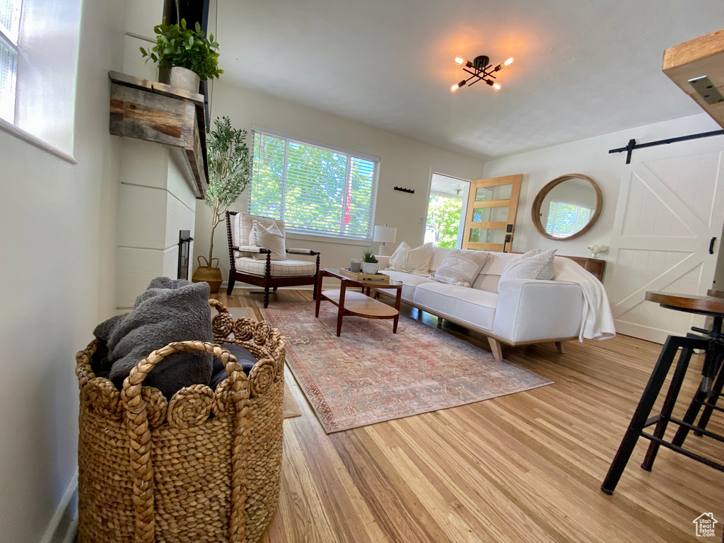 Living room with a barn door, light wood finished floors, and baseboards