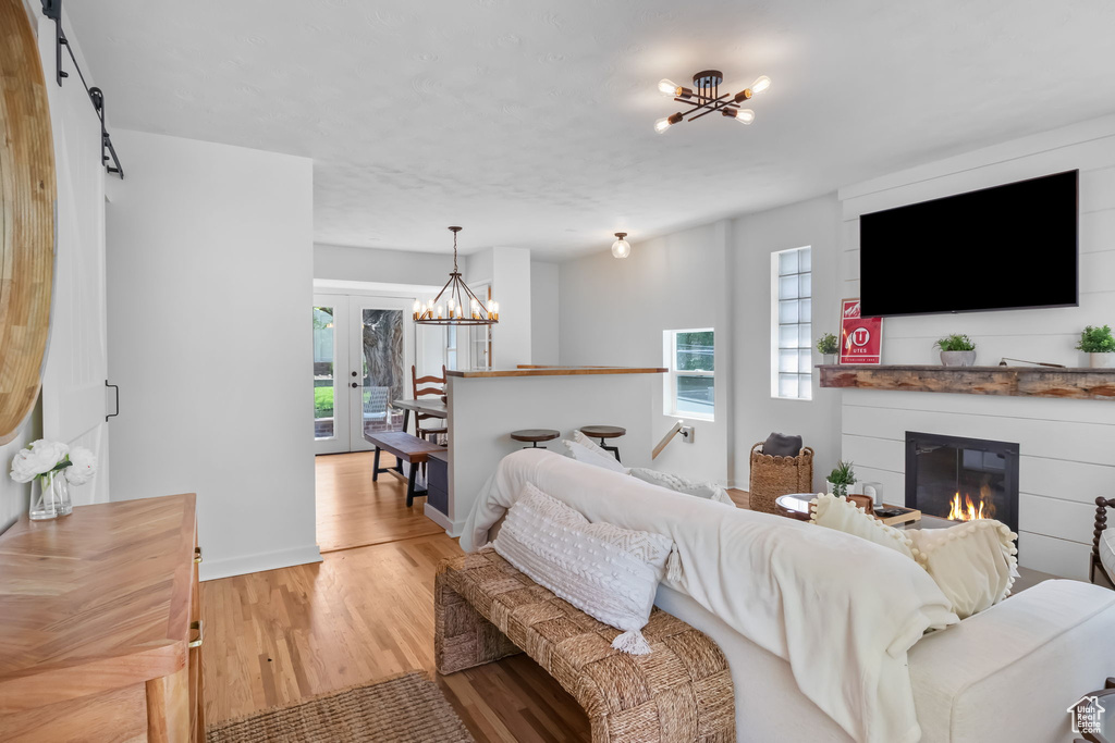 Living area with a chandelier, light wood-style flooring, a glass covered fireplace, and baseboards