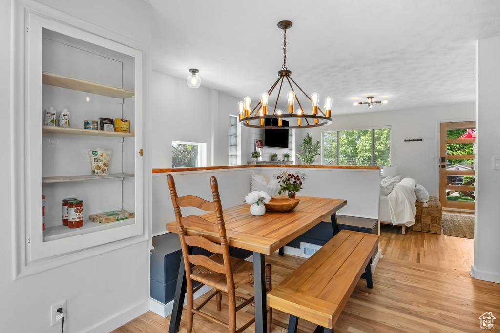 Dining room with a chandelier, light wood-type flooring, baseboards, and breakfast area