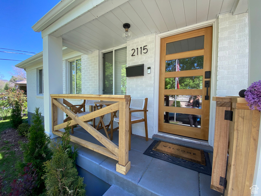 View of exterior entry with a porch and brick siding
