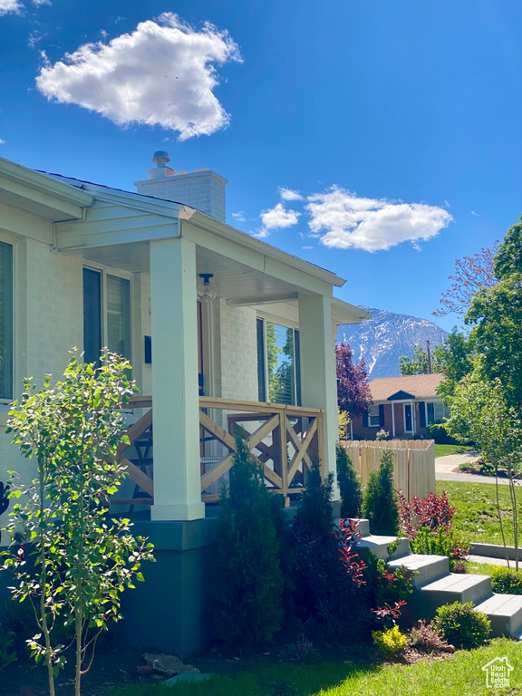 View of home\'s exterior with a chimney, a mountain view, and covered porch