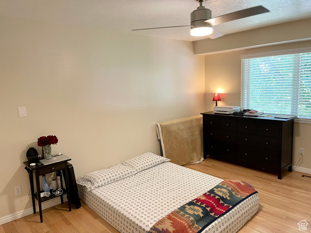 Bedroom with light wood-style floors, baseboards, and a ceiling fan