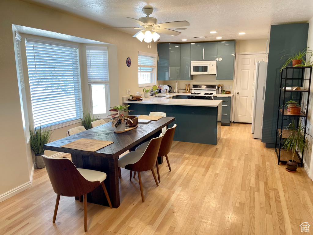 Dining space with light wood finished floors, ceiling fan, baseboards, a textured ceiling, and recessed lighting