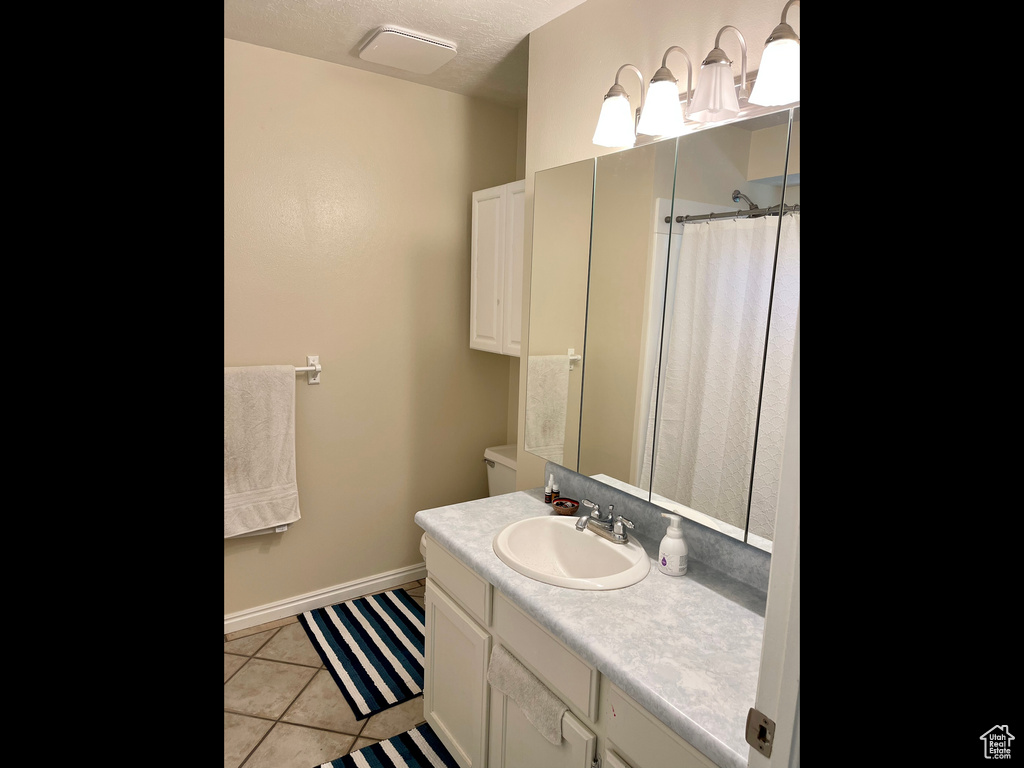 Bathroom with vanity, tile patterned floors, curtained shower, toilet, and baseboards