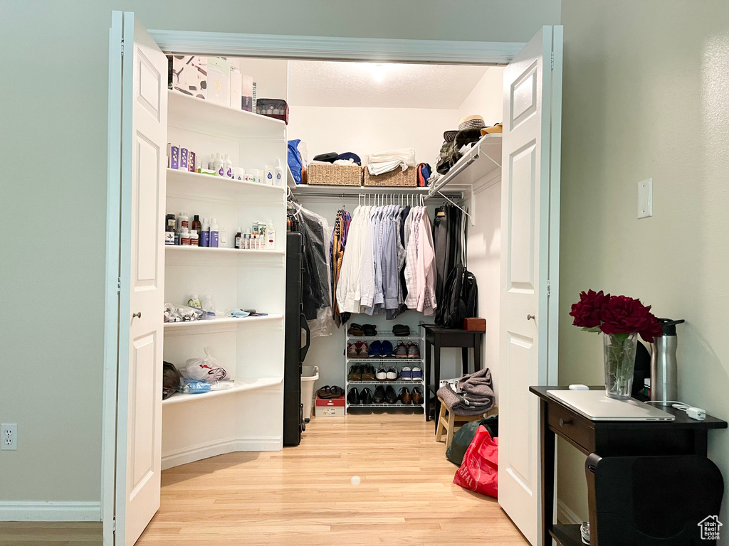 Walk in closet with light wood-type flooring