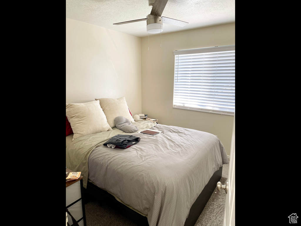 Bedroom featuring carpet floors, a ceiling fan, and a textured ceiling