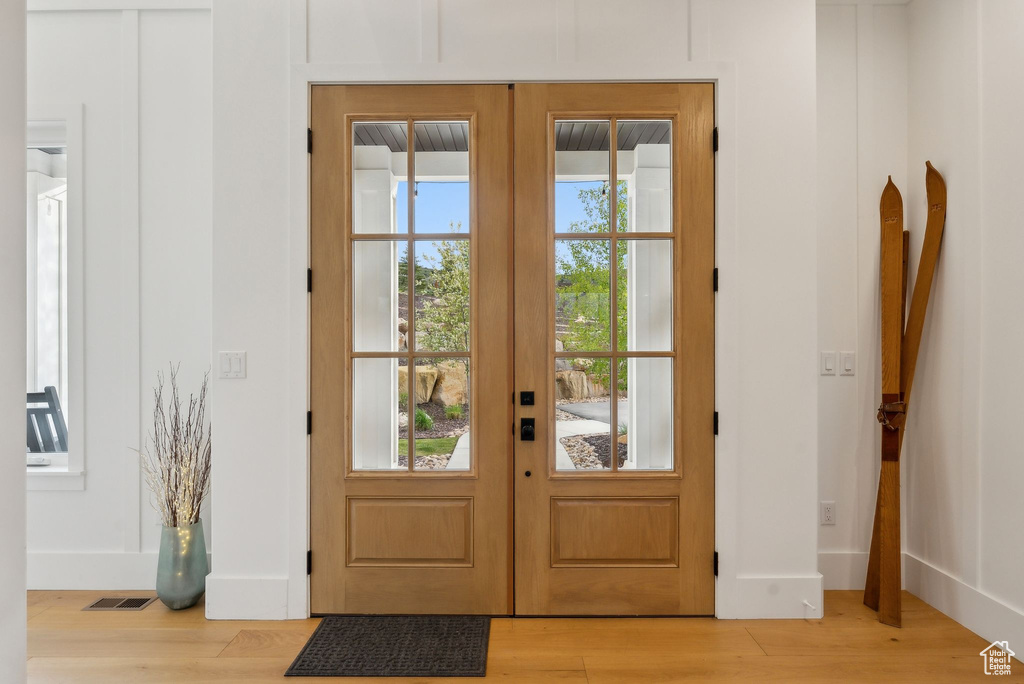 Doorway to outside featuring light wood-type flooring, french doors, and baseboards