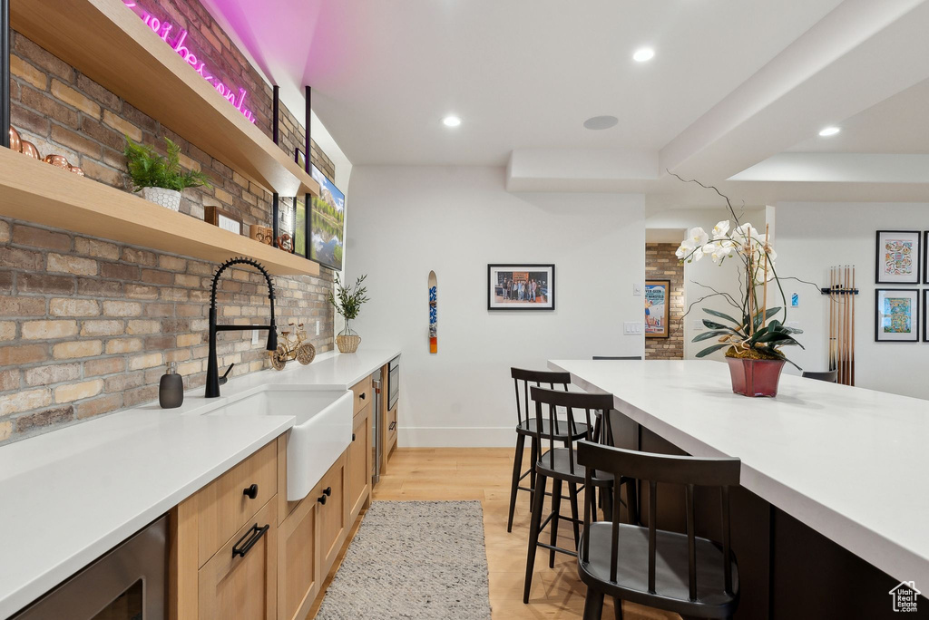 Kitchen featuring open shelves, a sink, a kitchen breakfast bar, baseboards, and recessed lighting