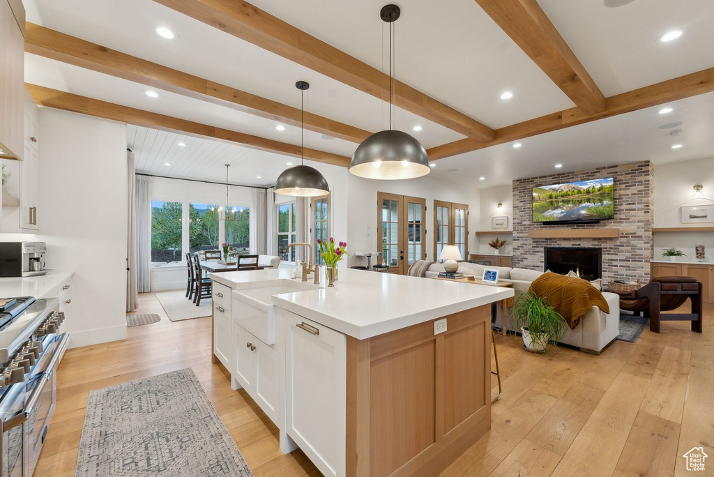 Kitchen featuring a sink, recessed lighting, light wood-style flooring, beamed ceiling, and double oven range