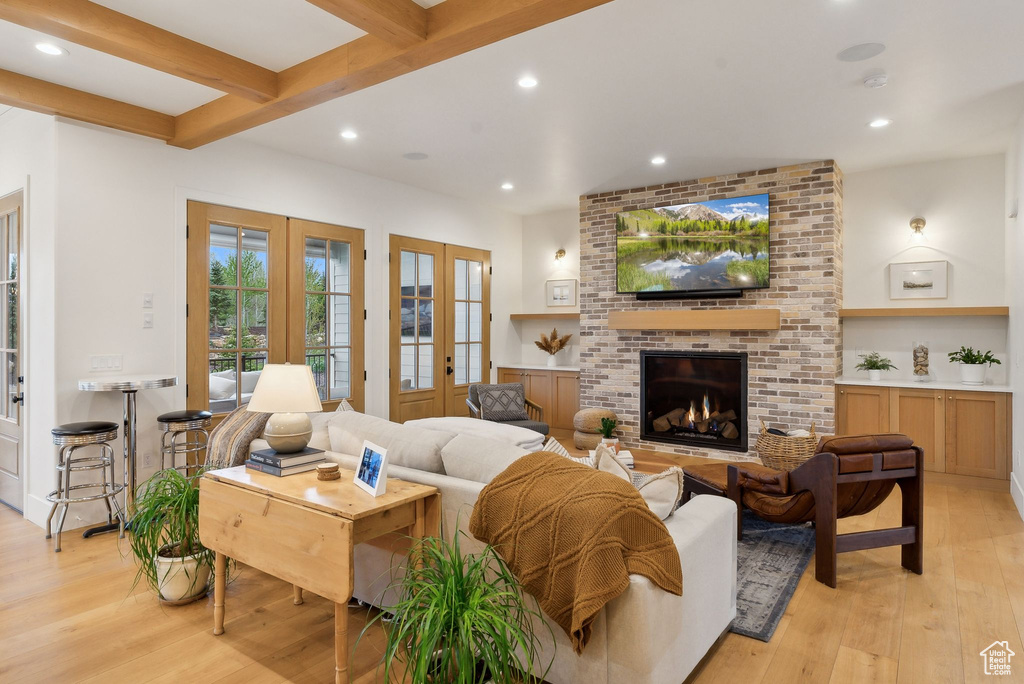 Living room featuring french doors, light wood finished floors, recessed lighting, a brick fireplace, and beam ceiling