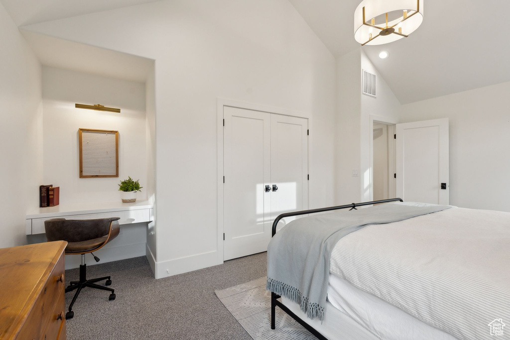 Carpeted bedroom featuring high vaulted ceiling, baseboards, a desk, and a closet