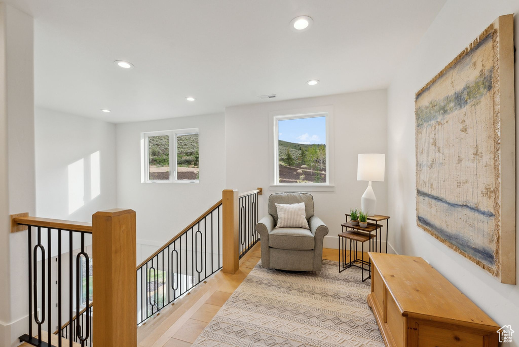 Sitting room with healthy amount of natural light, an upstairs landing, recessed lighting, and light wood-style flooring