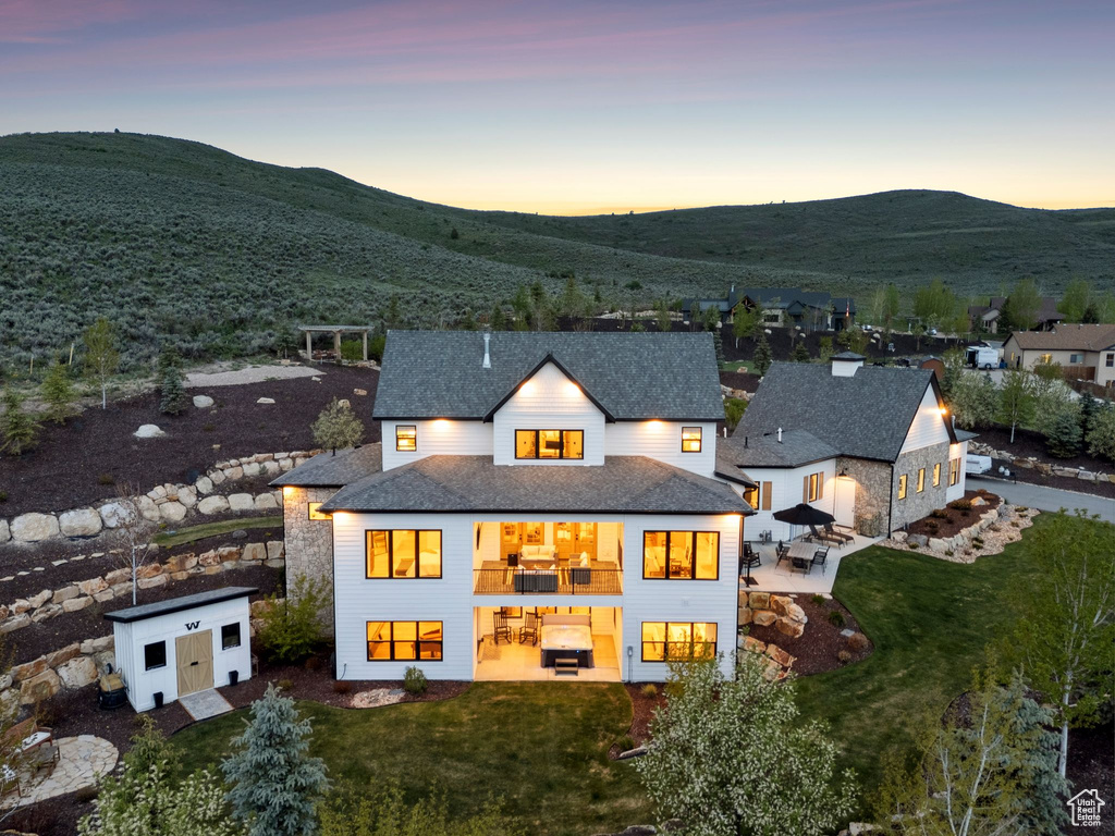 Back of property at dusk with an outbuilding, a patio, a storage unit, and a yard