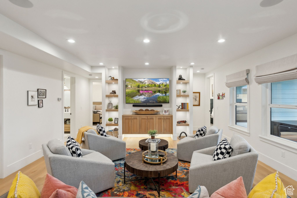 Living room with light wood-style floors, baseboards, recessed lighting, and built in shelves
