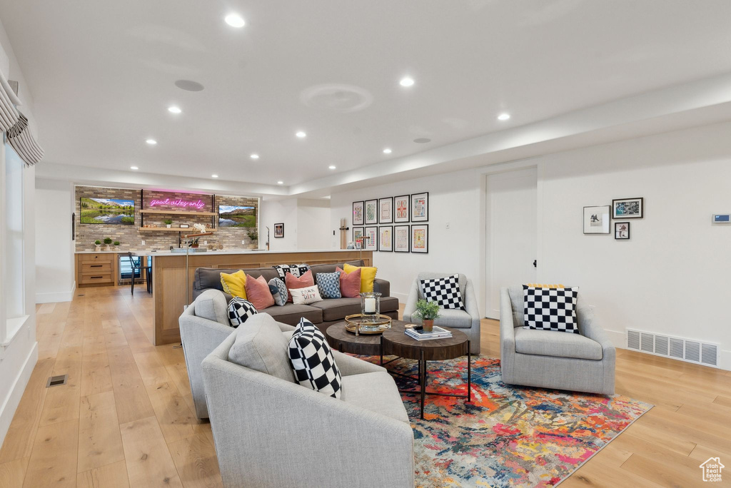Living room featuring light wood-style floors, recessed lighting, and bar area