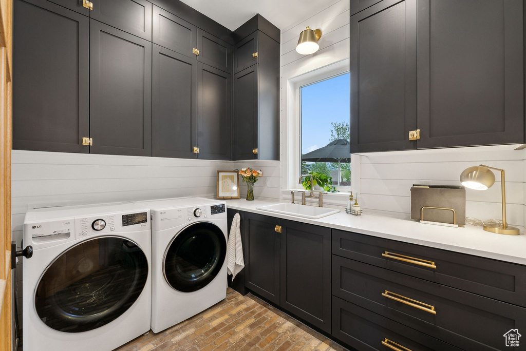 Washroom with cabinet space, washer and clothes dryer, and brick floors