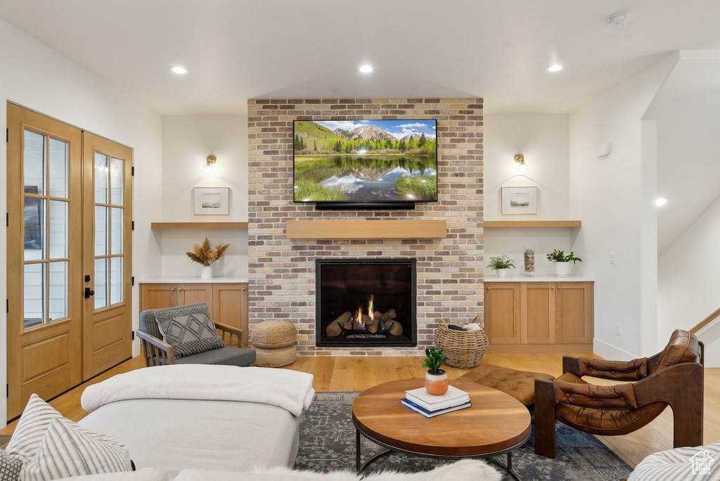 Living area featuring wood finished floors, french doors, recessed lighting, built in shelves, and a fireplace