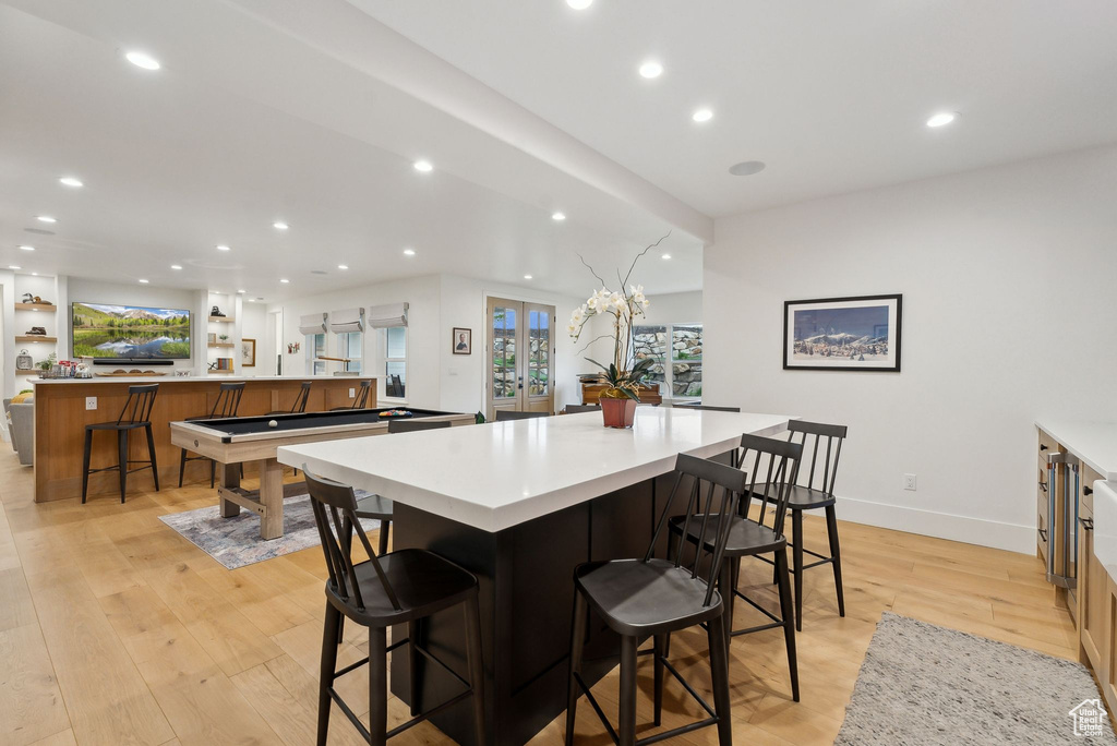 Kitchen featuring a large island, recessed lighting, light wood-style flooring, light countertops, and a breakfast bar