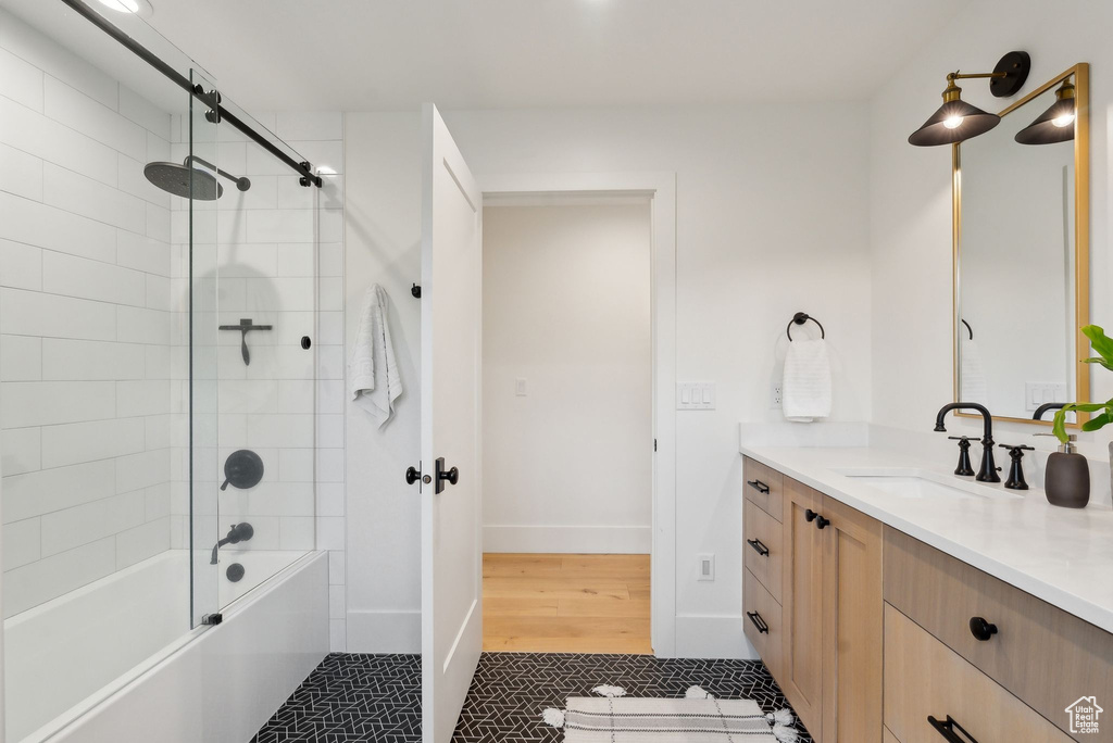 Bathroom featuring vanity, tile patterned floors, combined bath / shower with glass door, and baseboards