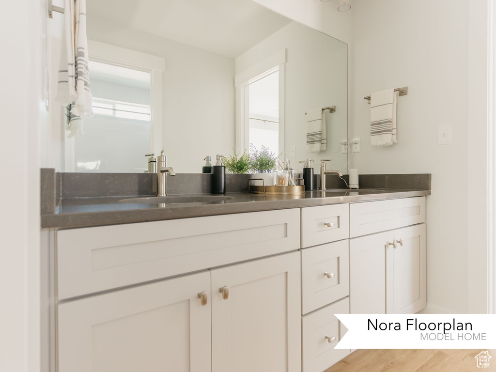 Bathroom featuring double vanity, plenty of natural light, and wood finished floors