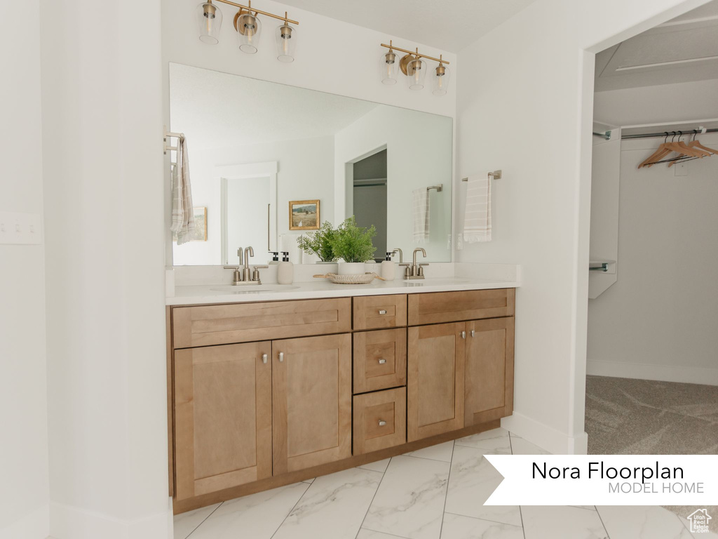 Full bath featuring double vanity, marble look tiles, and baseboards