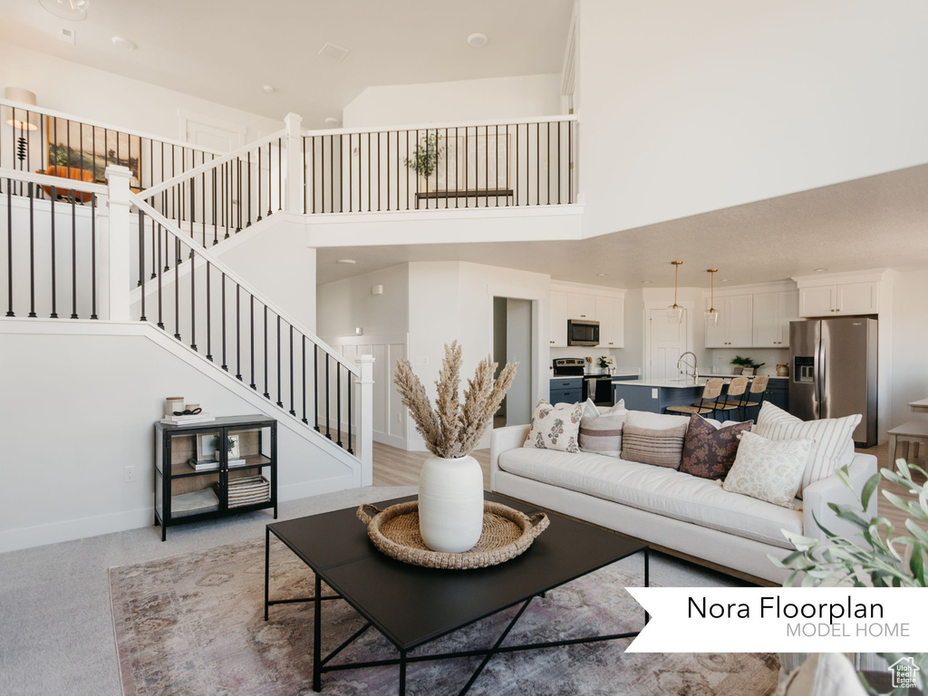 Living room featuring a high ceiling, stairway, light carpet, and baseboards