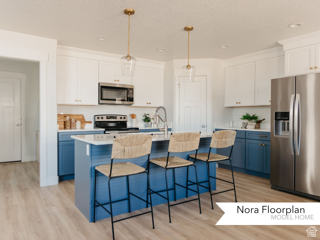 Kitchen featuring stainless steel appliances, light wood-style flooring, a sink, a kitchen breakfast bar, and recessed lighting