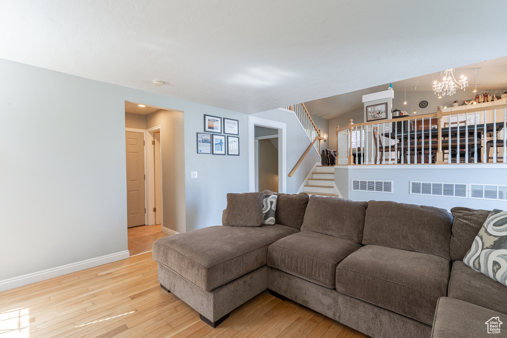 Living area featuring a chandelier, light wood-style floors, stairway, and baseboards