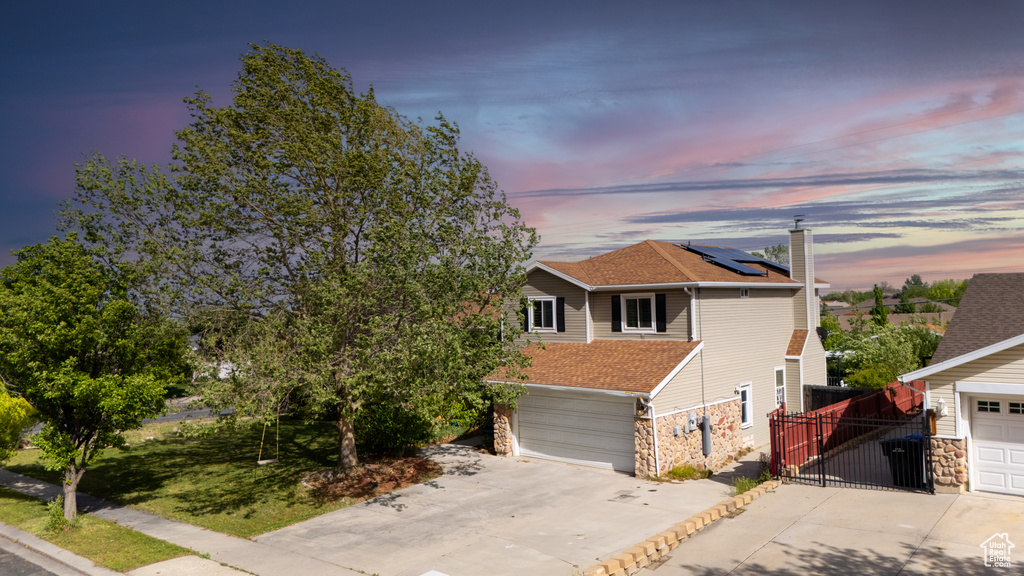 View of front of house featuring driveway, stone siding, fence, a shingled roof, and a chimney