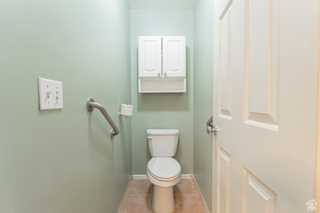 Bathroom featuring toilet, tile patterned flooring, and baseboards