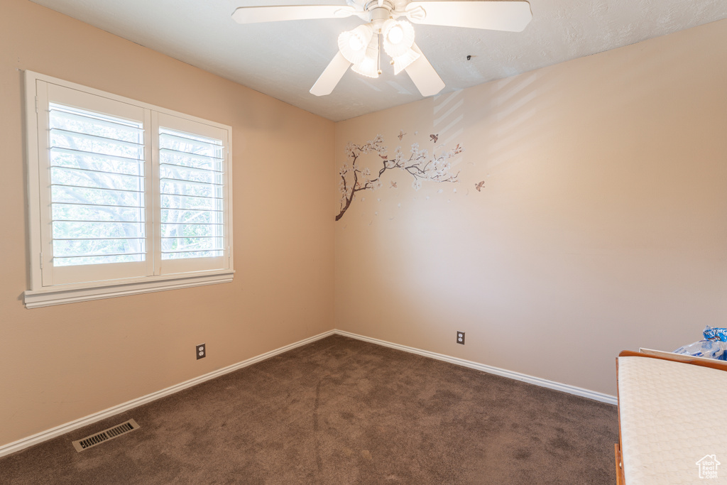 Unfurnished room with dark carpet, a ceiling fan, and baseboards