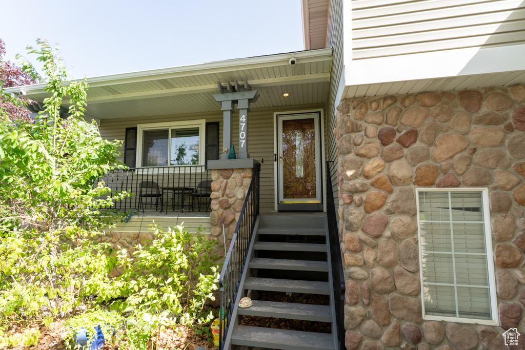 Property entrance with covered porch and stone siding