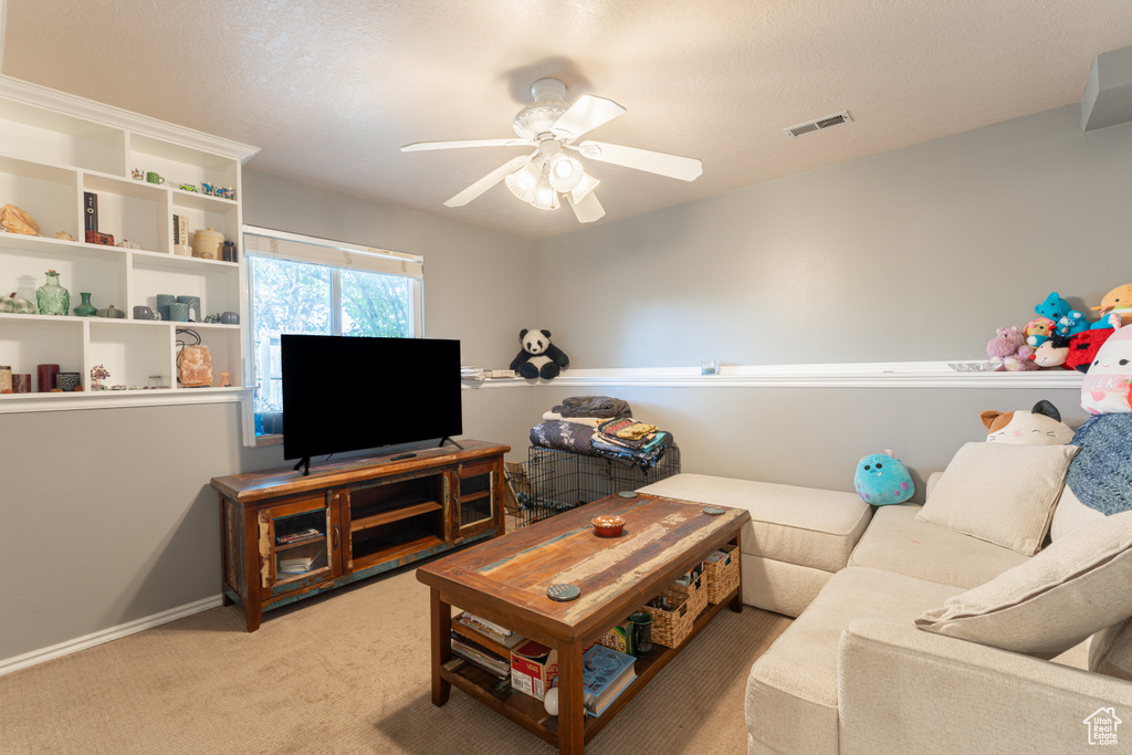 Living area featuring light colored carpet, a ceiling fan, and baseboards