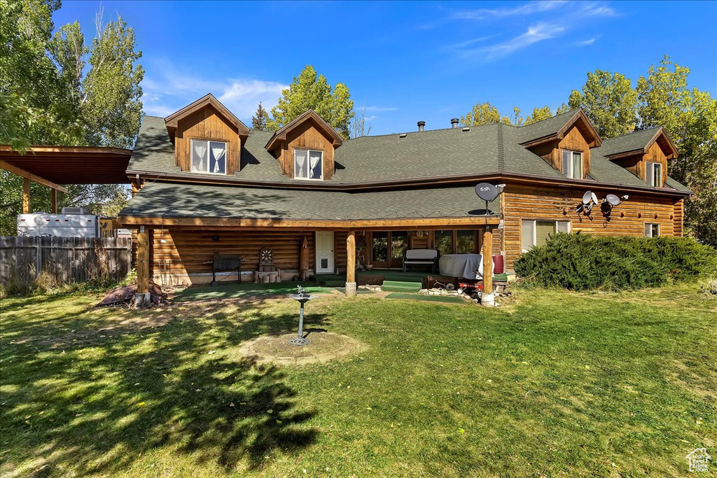 Back of property with a shingled roof, log exterior, and a patio