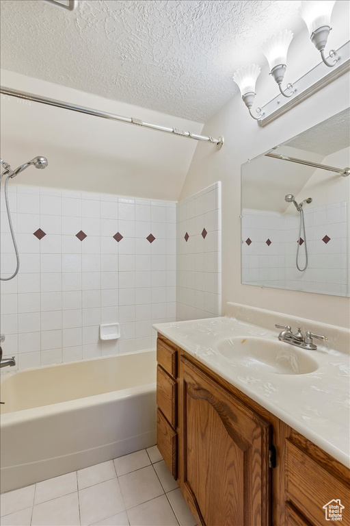 Full bathroom with tile patterned floors, lofted ceiling, bathing tub / shower combination, a textured ceiling, and vanity