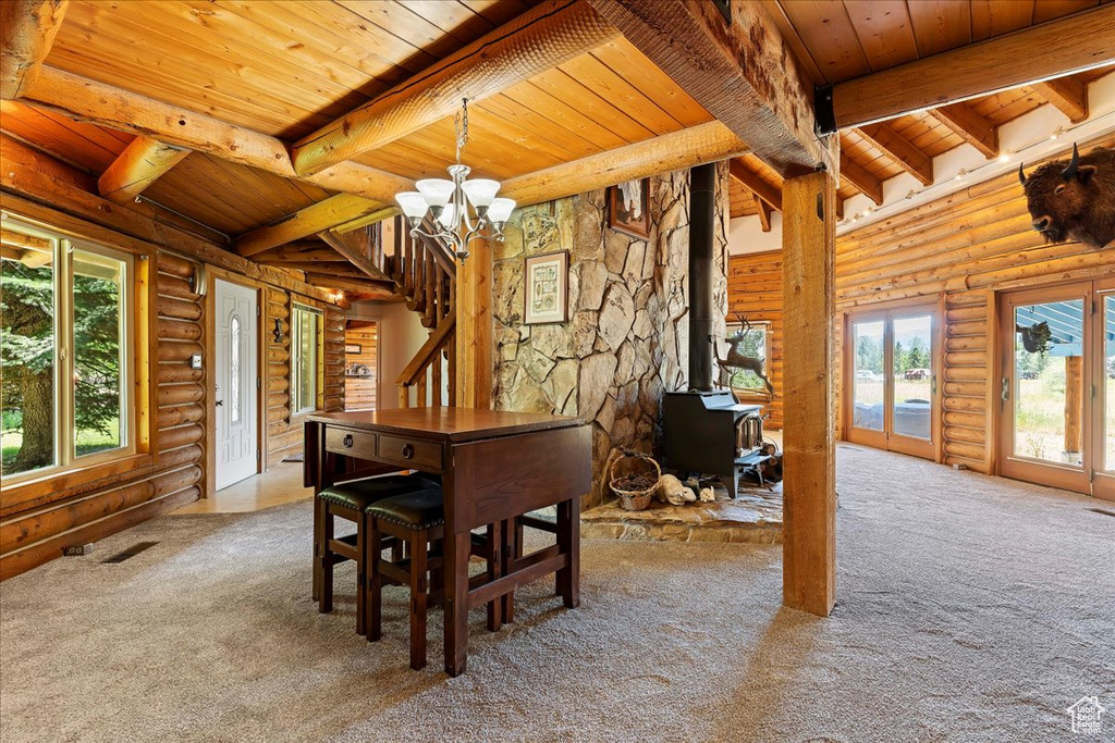 Dining room featuring wood ceiling, carpet flooring, beamed ceiling, log walls, and plenty of natural light
