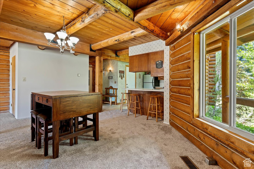 Dining area featuring wood ceiling, rustic walls, light carpet, a chandelier, and beam ceiling