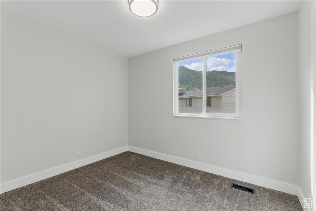 Spare room with dark colored carpet and baseboards
