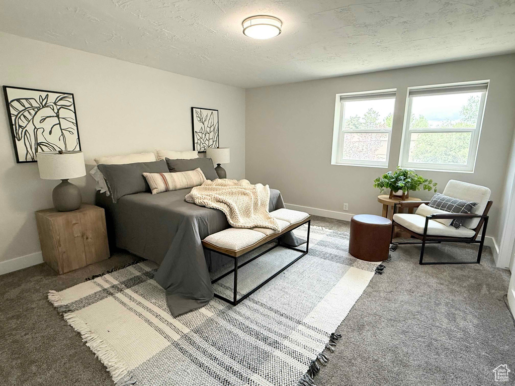 Carpeted bedroom featuring baseboards and a textured ceiling
