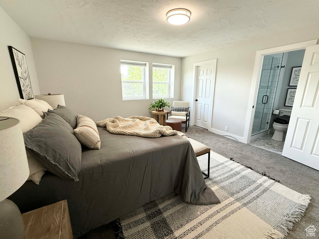 Bedroom featuring carpet, baseboards, ensuite bathroom, and a textured ceiling