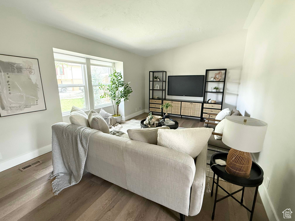 Living room featuring wood finished floors, baseboards, and vaulted ceiling