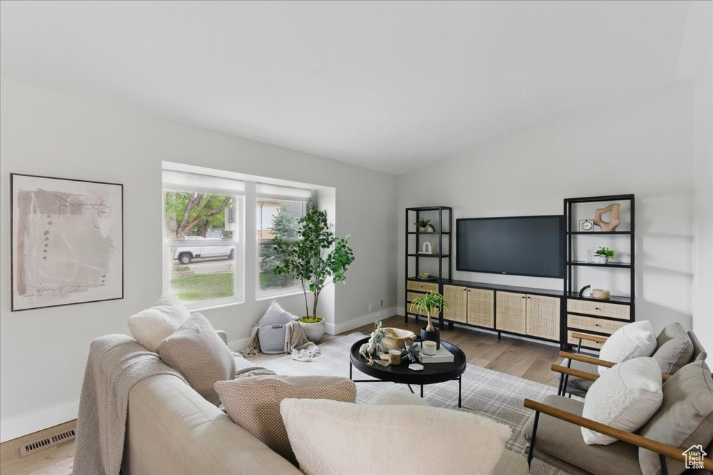 Living room featuring wood finished floors, baseboards, and lofted ceiling