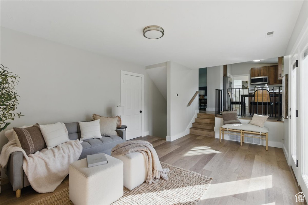 Living room featuring light wood-style floors, stairs, and baseboards