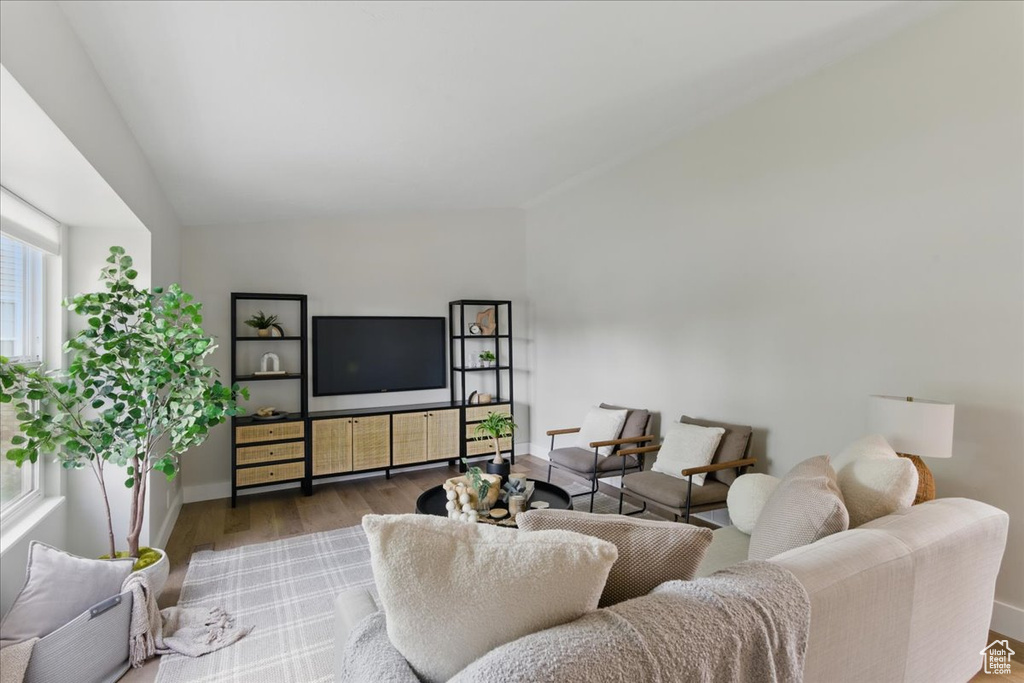 Living area featuring wood finished floors, vaulted ceiling, and baseboards