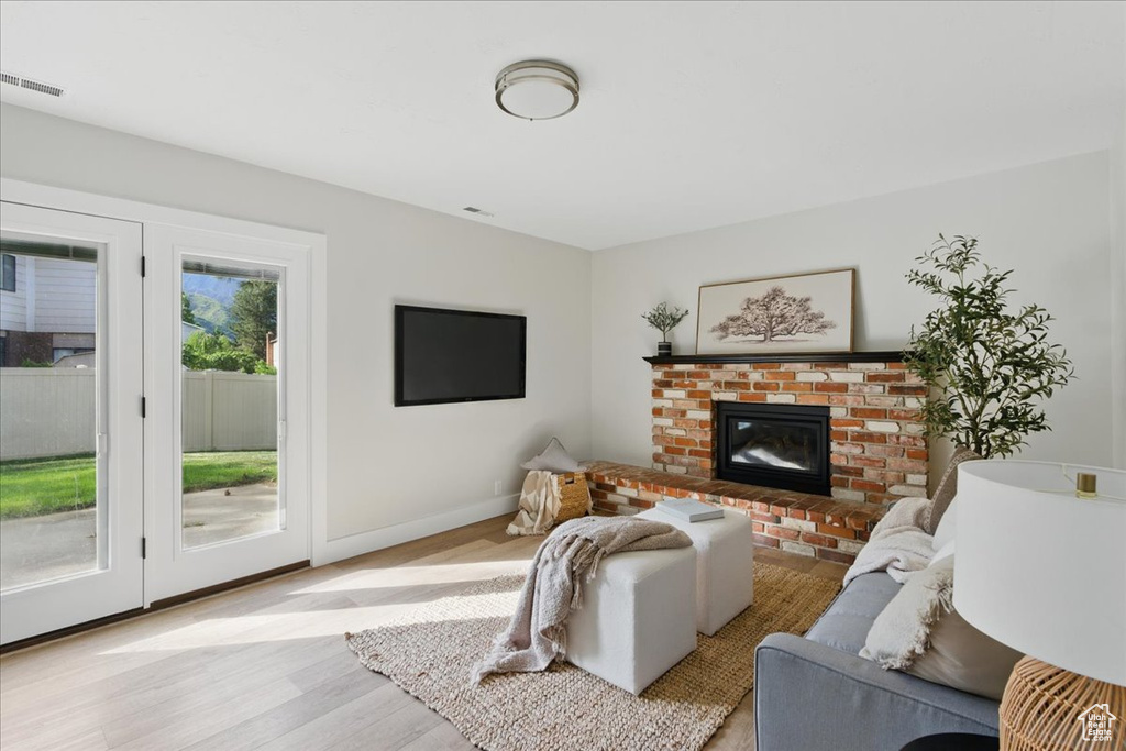 Living room featuring light wood-style flooring, a brick fireplace, and baseboards