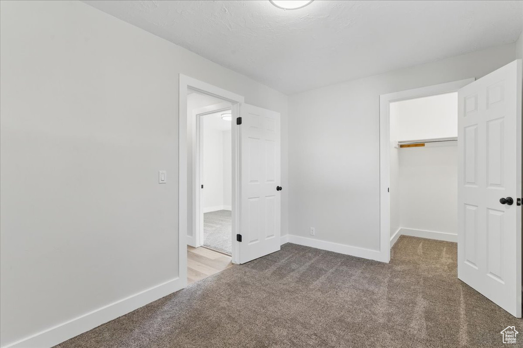 Unfurnished bedroom featuring carpet, baseboards, a spacious closet, and a closet