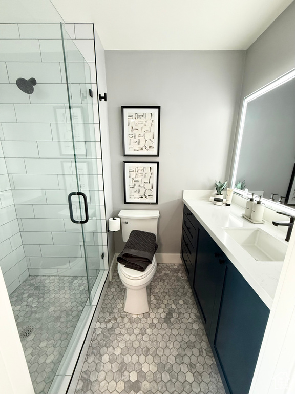 Bathroom featuring toilet, a stall shower, vanity, tile patterned floors, and baseboards